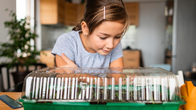 Foto gratuita niña viendo crecer los cultivos en casa