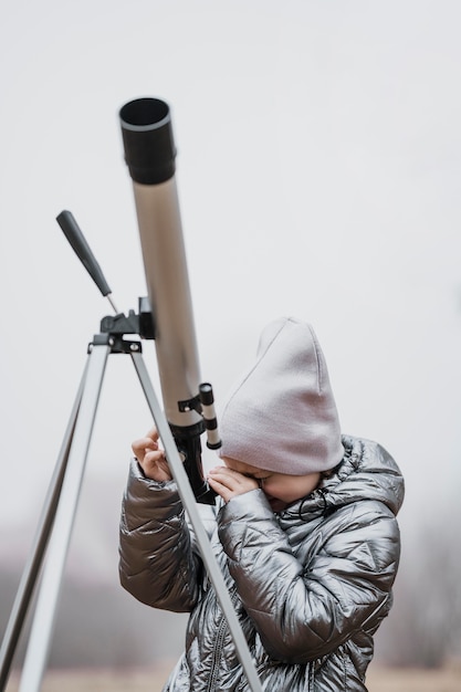 Niña de vista frontal con un telescopio