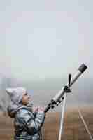 Foto gratuita niña de vista lateral con un telescopio