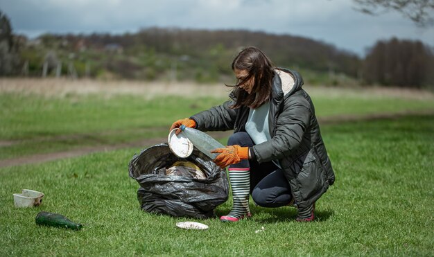 Niña voluntaria recoge basura en el bosque, cuida el medio ambiente.