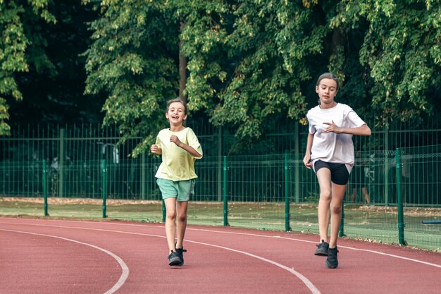 Foto gratuita niñas adolescentes de fitness infantil corriendo en la pista del estadio