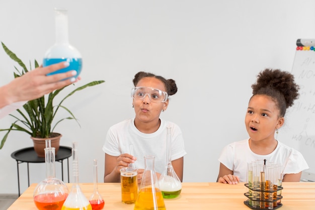 Niñas aprendiendo sobre química con pociones y tubos.