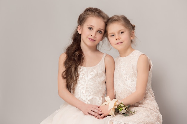 Niñas bonitas con flores vestidas con vestidos de novia