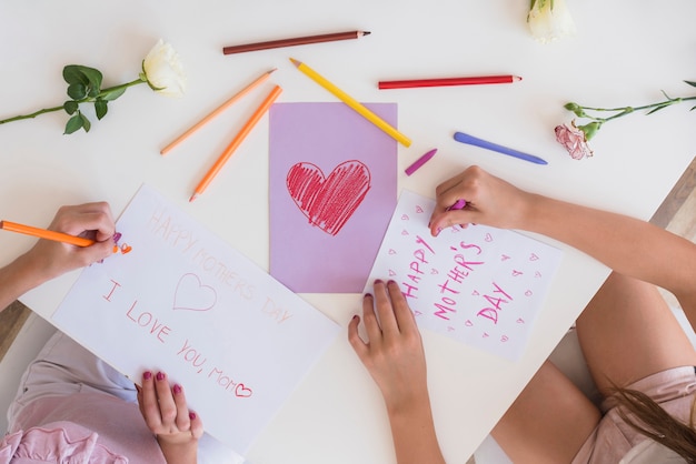 Niñas dibujando tarjetas de felicitación para el día de la madre.