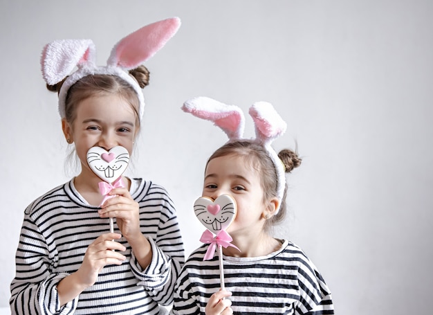 Niñas divertidas con orejas de Pascua en la cabeza y pan de jengibre de Pascua en palos.