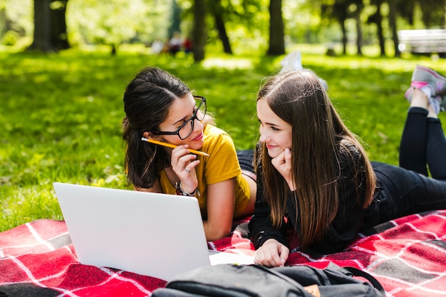 Niñas estudiando y tumbadas en el parque