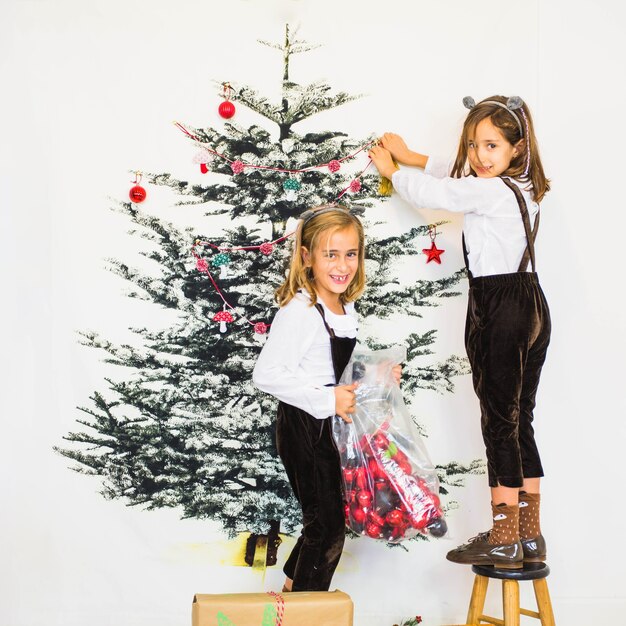 Niñas felices decorando árbol de navidad