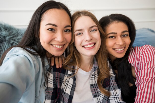 Niñas felices tomando selfie y sonriendo mirando a cámara