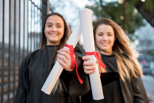 Foto gratuita niñas en la graduación mostrando sus certificados.