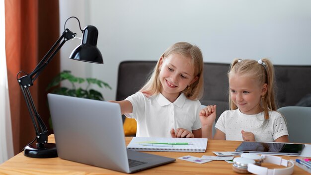 Niñas haciendo escuela en línea juntas en casa