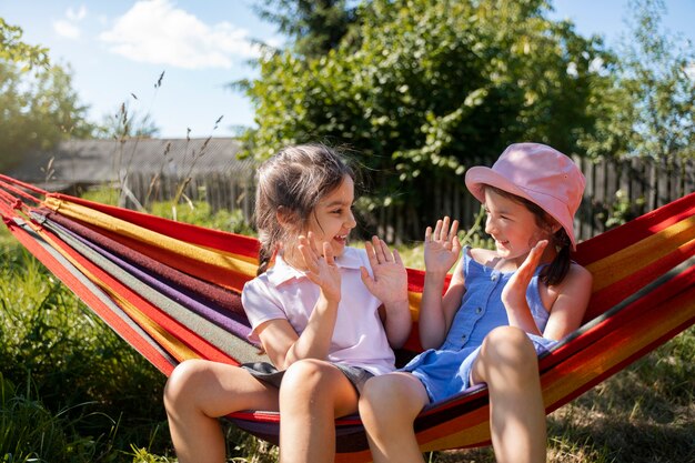 Niñas jugando al aire libre juntas y sentadas en una hamaca