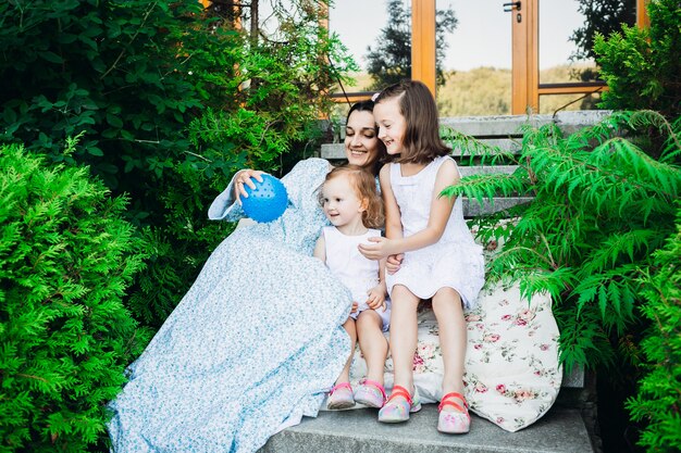 Las niñas y la madre en vestido azul juegan con pequeña bola azul