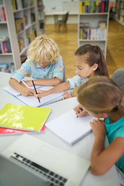 Niñas y niños haciendo lecciones en la biblioteca.
