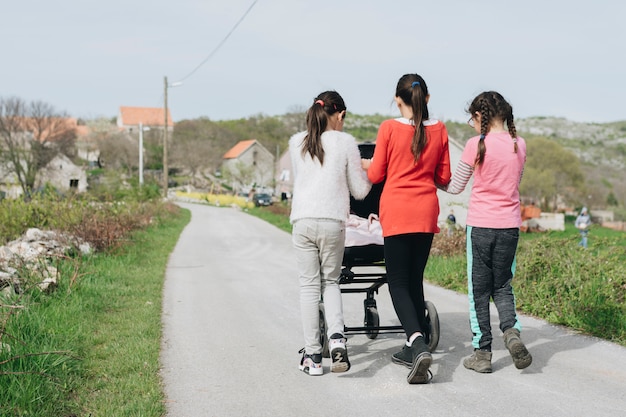 Foto gratuita niñas paseando bebé en pueblo