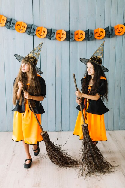Foto gratuita niñas en ropa de hechicera sosteniendo palos de escoba