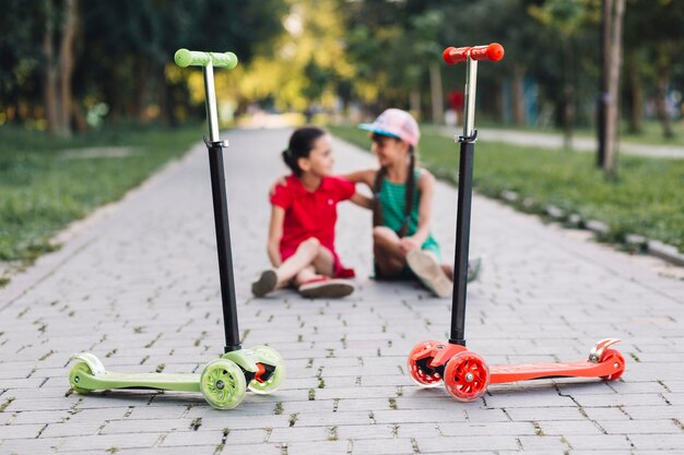 Niñas sentadas detrás de las motos de empuje en la pasarela del parque