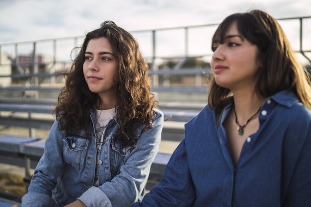 Niñas sentadas y hablando entre sí detrás de una valla metálica durante el día