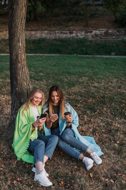 Niñas sentadas en el parque junto a un árbol