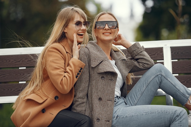 Las niñas sentadas en una primavera sity y sostienen el café en la mano