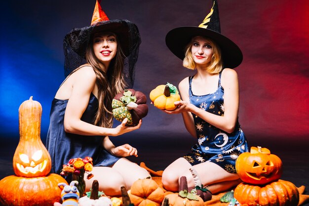 Niñas en sombreros de brujas sosteniendo calabazas