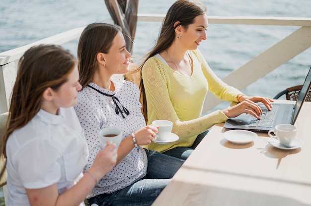 Foto gratuita niñas sonrientes de alto ángulo con tazas y laptop