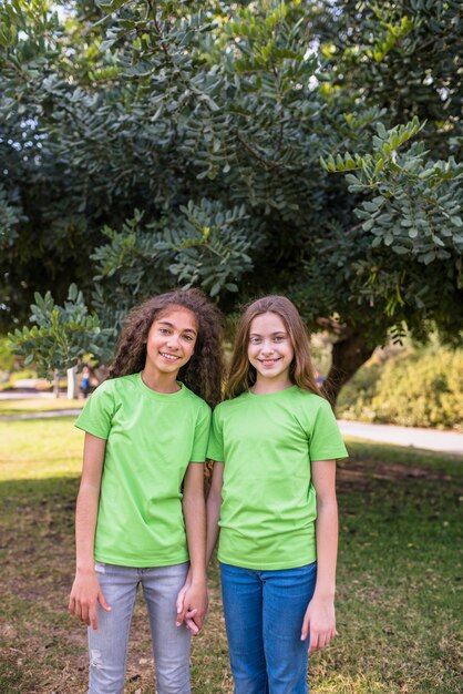 Niñas sonrientes de pie delante de un árbol en el parque