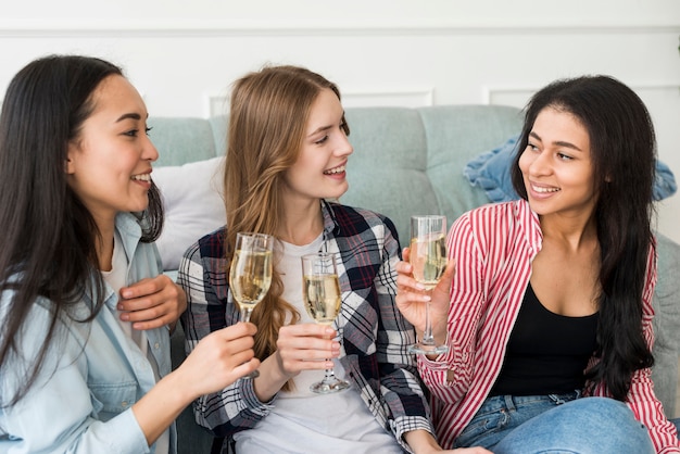 Niñas sonrientes sentados y sosteniendo vasos con bebida en manos