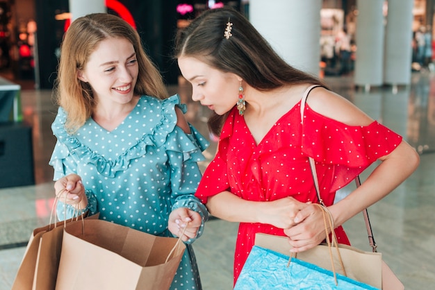 Niñas de tiro medio revisando sus bolsas de compras.