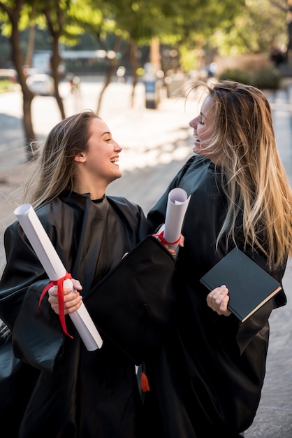 Niñas de tiro medio siendo alegres en su graduación.