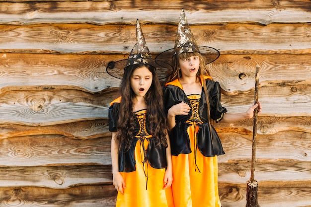Niñas con trajes de bruja haciendo caras sobre fondo de madera