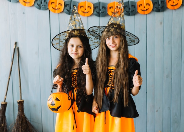 Niñas con trajes de bruja sonriendo con los pulgares arriba