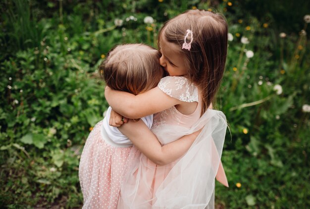 Las niñas en vestidos de color rosa corren en un césped verde