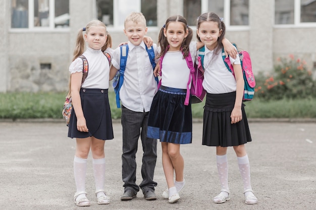 Niño abrazando chicas cerca de la escuela