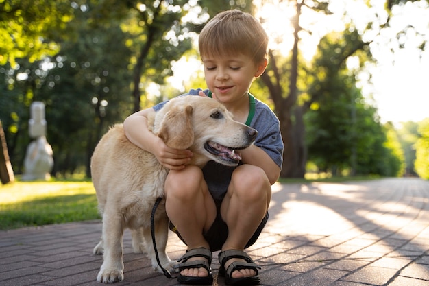 Niño abrazando a un perro de tiro completo en el parque