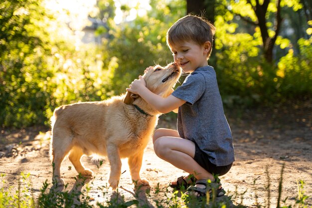 Niño abrazando a perro de tiro completo