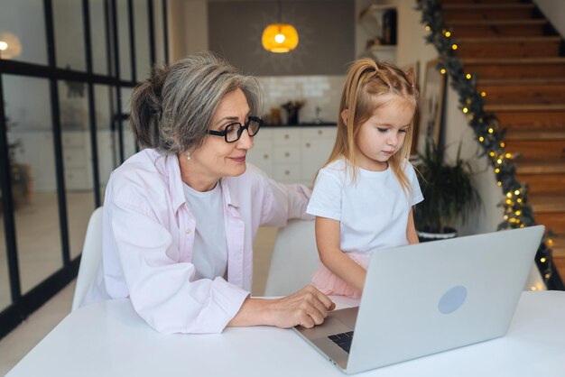 Niño y abuela mirando a la cámara con una laptop en casa