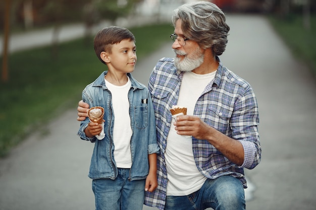 Niño y abuelo están caminando en el parque. Anciano jugando con su nieto. Familia con helado.