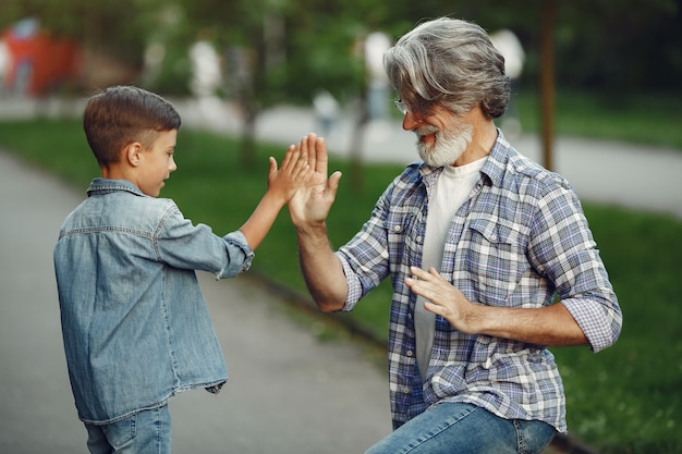 Niño y abuelo están caminando en el parque. Anciano jugando con su nieto.