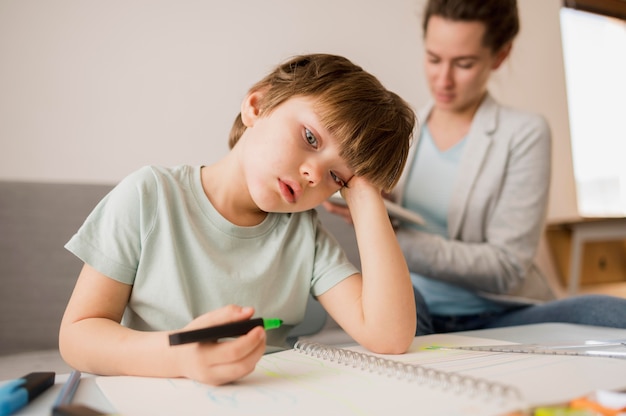 Niño aburrido en casa mientras recibe tutoría