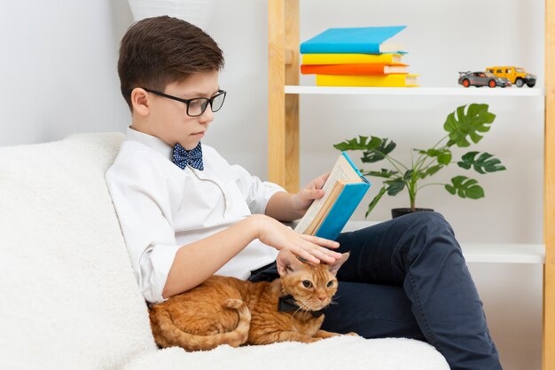 Niño acariciando gato y leyendo