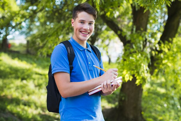 Niño adolescente sonriente haciendo notas