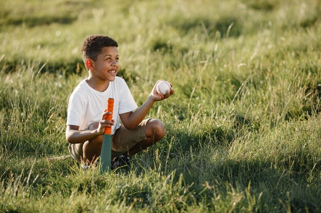 Niño africano. Niño en un parque de verano. El niño juega en el fútbol americano.