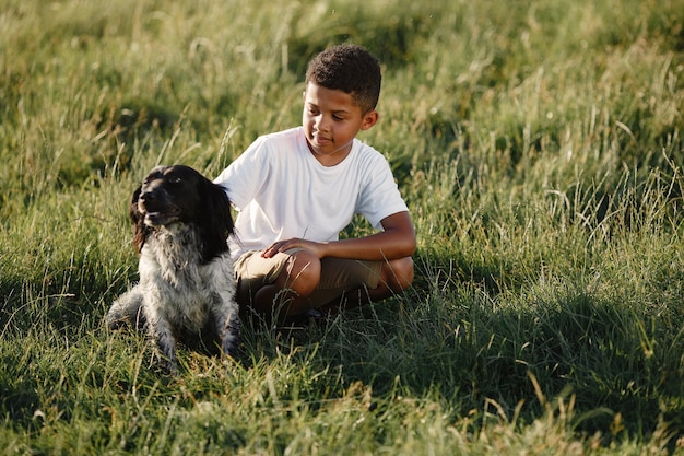 Niño africano. Niño en un parque de verano. Niño juega con perro.