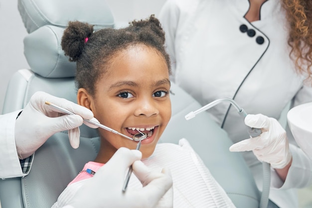 Niño afro feliz en chequeo regular de dientes en clínica dental
