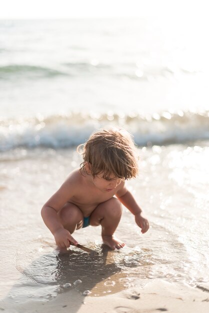 Niño agachado jugando en la playa