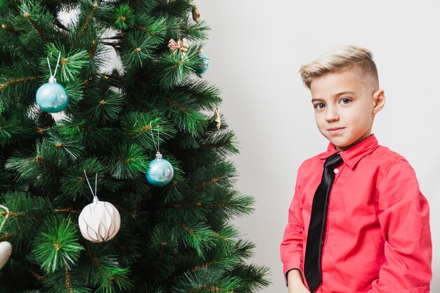 Niño al lado de árbol de navidad