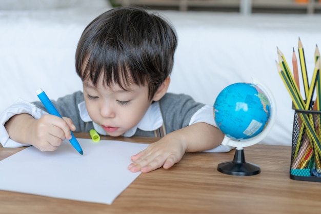 Niño alegre con dibujo a lápiz de color naranja sobre papel blanco