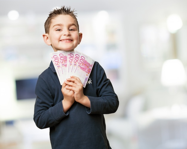 Niño alegre con un montón de billetes