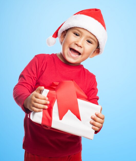 Niño alegre sujetando su regalo con las dos manos