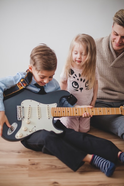 Niño alegre tocando la guitarra de su padre